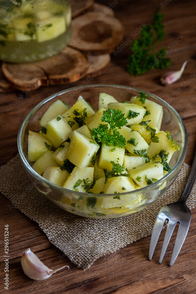 Marinated zucchini with herbs in a transparent cup on a wooden table Marinated zucchini with herbs in a transparent cup on a wooden table
