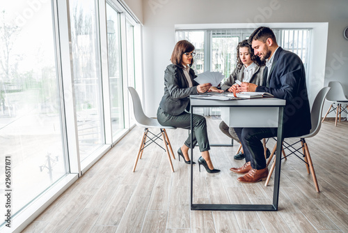Wide angle of group business people in bright spacious modern office . Young businessman and businesswoman sitting at the desk in design studio with woman sales manager. Work with client concept