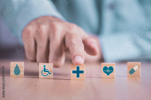 Businessman chooses a emoticon icons healthcare medical symbol on wooden block , Healthcare and medical Insurance concept