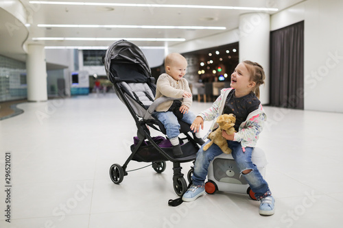 child with suitcases and baby in stroller, airport