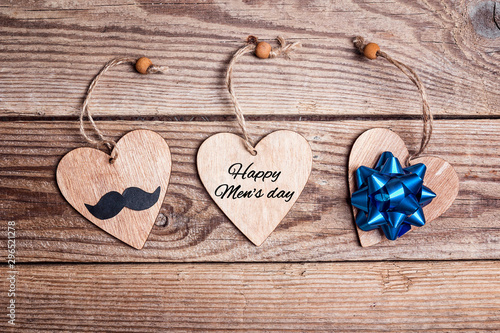 World men's day card with hearts, mustache and bow on old wooden table.