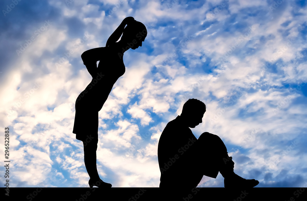 Silhouette of a standing woman leaned over a man who sits on the floor, clasping his legs