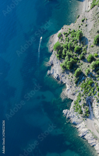 Stone cliff with bushes in the sea and a boat, from top to bottom. landscape below (aerial photo from a paraglider) with the coast and the blue sea, Montenegro