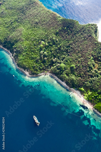 Green forested cliff (Paradise island) with a motor yacht parked at it. landscape below (aerial photo from a paraglider) with the coast and the blue sea, Montenegro