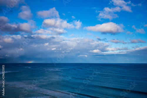 Regenbogen hinter den Wolken über dem Meer