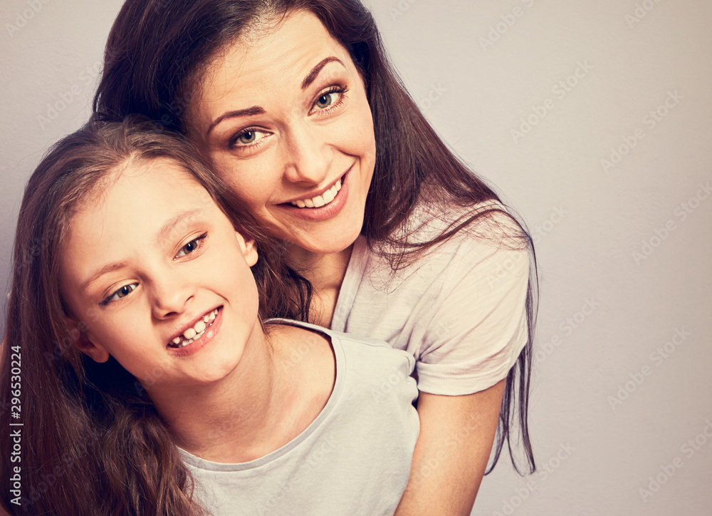 Happy smiling emotion mother cuddling her cute daughter sitting on the floor with love on purple background with empty copy space. Closeup Happy smiling emotion mother cuddling her cute daughter sitting on the floor with love on purple background with empty copy space. Closeup