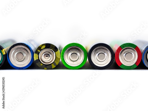 Old AA batteries of different colors are stacked in a line. Batteries on white background