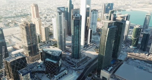 Aerial rising view of a business districts filled with towers and high rise buildings in a futuristic developped city, Doha, capital of Qatar photo