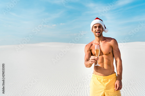 sexy man in santa hat holding champagne glass on beach in Maldives