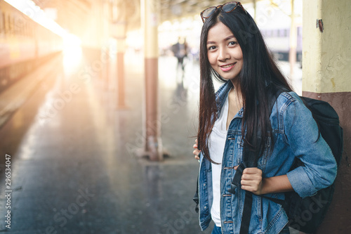 Portrait of young asian woman smiling  and waiting at train station. Travel concept. © amornchaijj