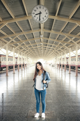 Portrait of young asian woman smiling and waiting at train station. Travel concept.