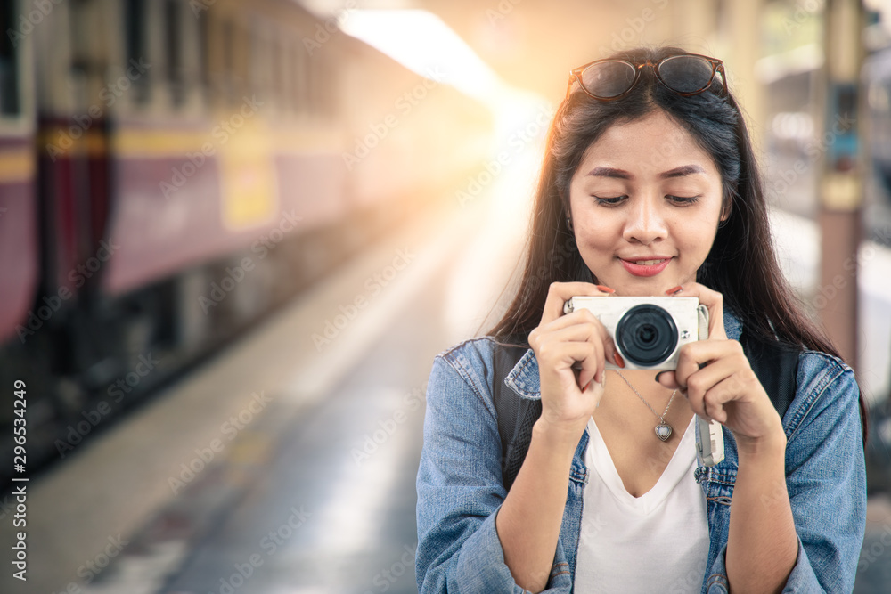 Portrait of an Asian woman smiling and take photo at the train station. Tourism concept