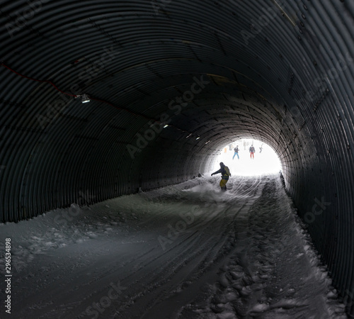 Snowboarder in motion on slopes snow park has entered into a tunnel in ski resort