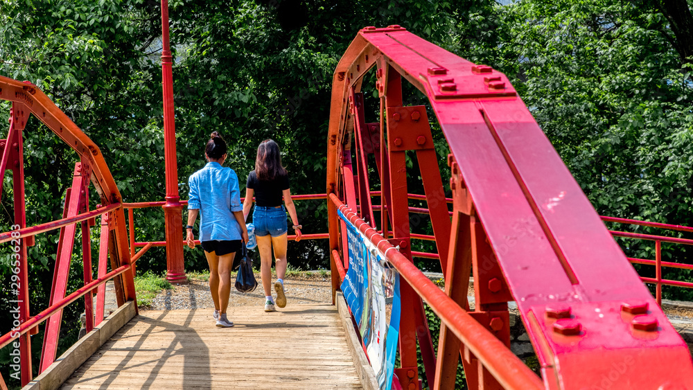 Mother and teen daughter walking across red bridge Mother and teen daughter walking across red bridge