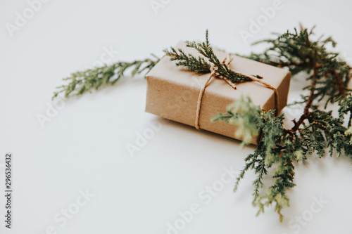 Bright green twigs of pine tree and a light brown gift box on the white background. Isolated Copyspace christmas flat lay concept. 