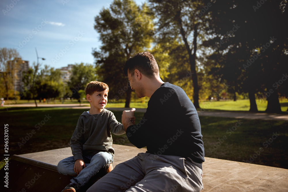 Father and son sitting on a skate ramp and talking Father and son sitting on a skate ramp and talking