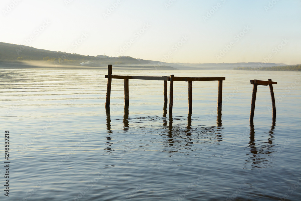 Wooden boat dock under construction on the river Danube during the blue hour. View of the vastness of the river. A metaphor for peace, serenity, sadness, loneliness, unfinished. Wooden boat dock under construction on the river Danube during the blue hour. View of the vastness of the river. A metaphor for peace, serenity, sadness, loneliness, unfinished.