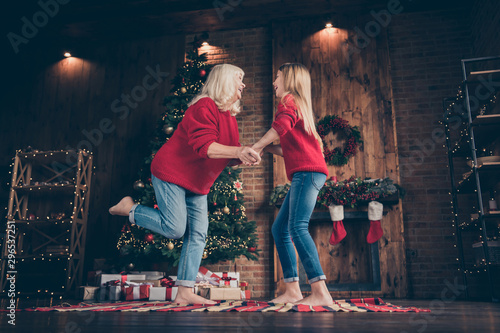 Full length body size view of nice attractive cheerful cheery granny pre-teen grandchild dancing having fun holly jolly festive at decorated industrial brick wood loft style interior house