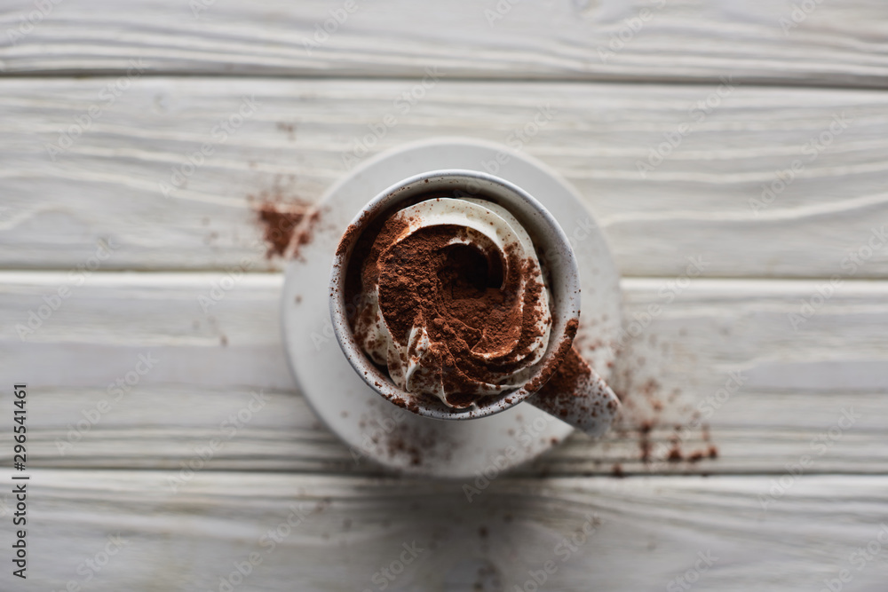 selective focus of Christmas cacao in mug with whipped cream and cacao powder on white wooden table selective focus of Christmas cacao in mug with whipped cream and cacao powder on white wooden table