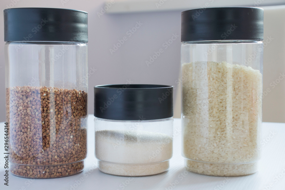 cereals in transparent jars on a white table. buckwheat, sugar, rice. cereals in transparent jars on a white table. buckwheat, sugar, rice.
