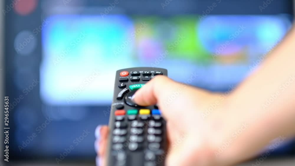 slow motion woman watches TV and presses a button on the remote control. hand holding the TV remote control and turn off smart tv. Channel surfing. blurred background slow motion woman watches TV and presses a button on the remote control. hand holding the TV remote control and turn off smart tv. Channel surfing. blurred background