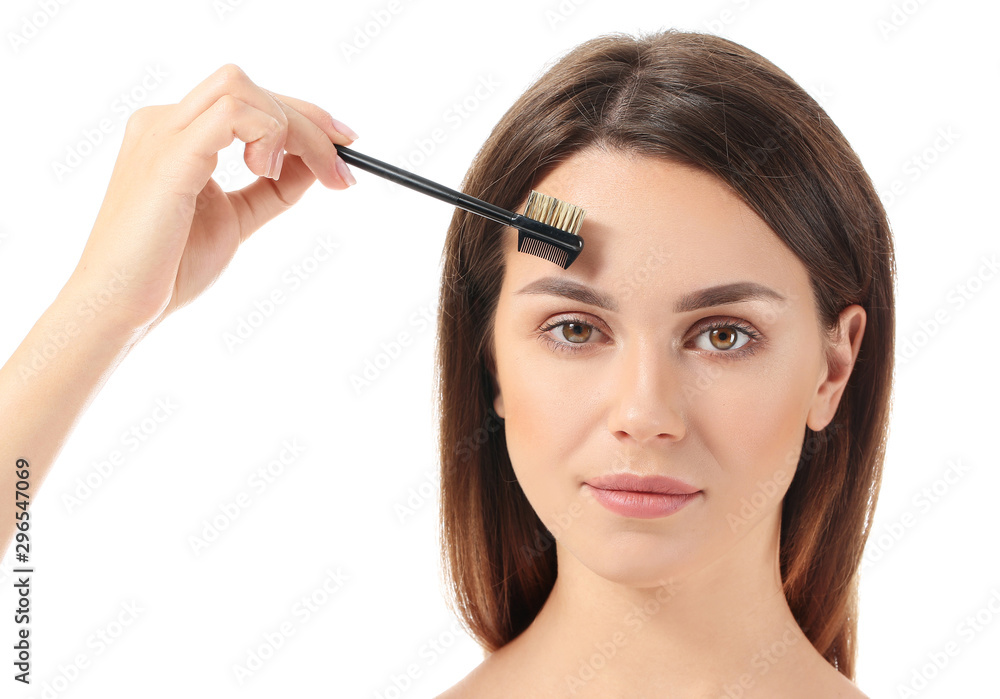 Fototapeta premium Beautiful young woman with makeup brush on white background