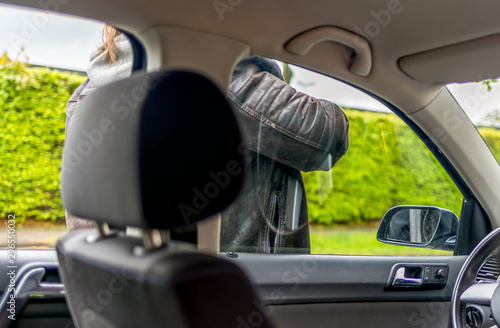 person tries to smash the window on a car with his arm