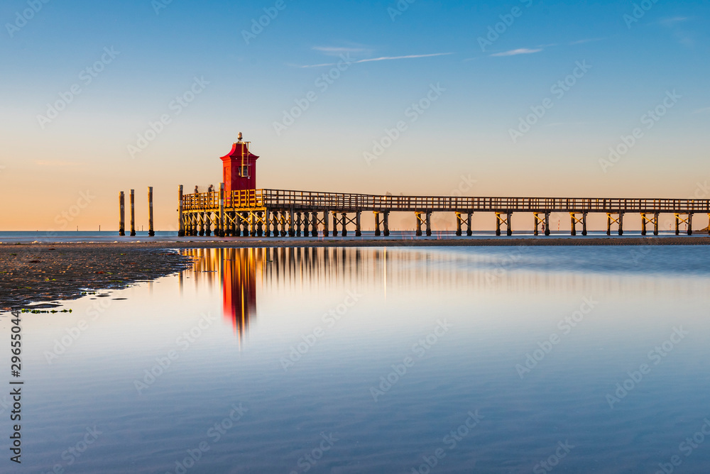 Sunrise over the sea. The lighthouse of Lignano Sabbiadoro and the games of sand and colors. Italy