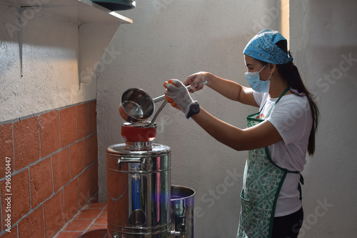 Woman pouring fermented alcoholic juice in stainless dispenser  in a home based winery. side view shot
