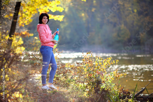 Girl in the yellow autumn forest. Beautiful mature woman in a forest with a bottle of champagne in hand.