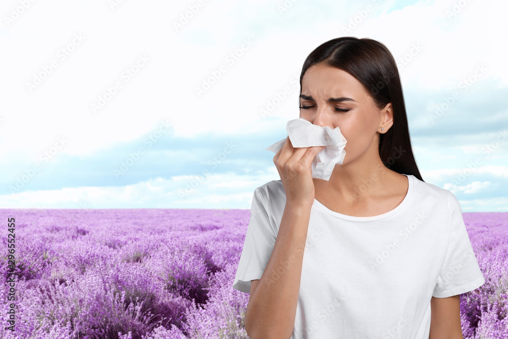 Young woman suffering from allergy and blooming lavender field on background