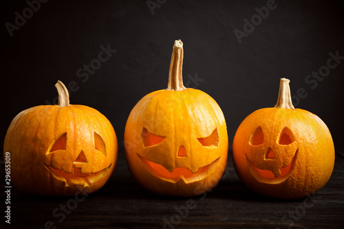 Spooky Jack pumpkin head lanterns on wooden table against black background. Halloween decoration