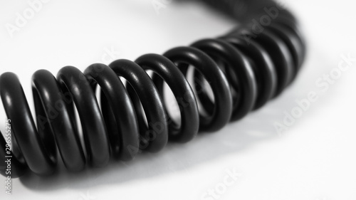 Black coiled cable on white table. Close up with shallow depth of field.