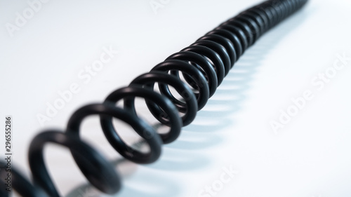 Black coiled cable on white table, diagonal left to right. Close up with shallow depth of field.