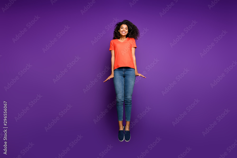 Full length body size photo of cheerful positive pretty sweet beautiful girl wearing jeans denim stretching up jumping isolated violet bright color background Full length body size photo of cheerful positive pretty sweet beautiful girl wearing jeans denim stretching up jumping isolated violet bright color background