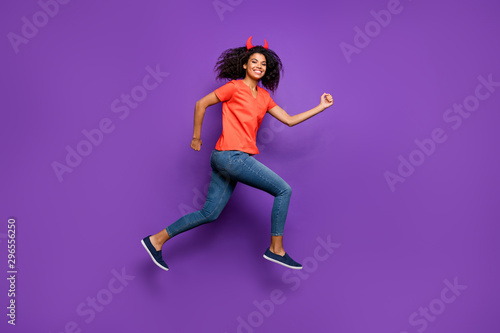 Fototapeta Naklejka Na Ścianę i Meble -  Full length body size side profile photo of cheerful cute excited girl aspiring ahead for sales wearing jeans denim orange t-shirt smiling toothily jumping running isolated vivid violet color