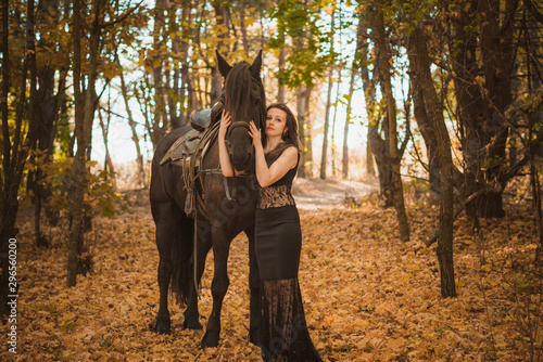 Concept of feminity. Young woman in a black dress with a horse. Beautiful girl with black horse  © T.Den_Team