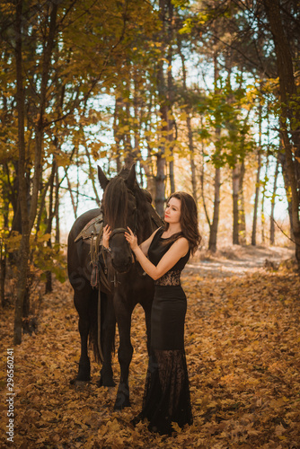 Concept of feminity. Young woman in a black dress with a horse. Beautiful girl with black horse  © T.Den_Team