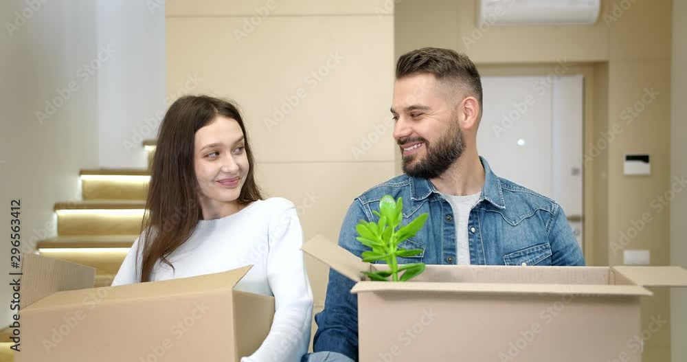 Joyful young man and lady standing in empty flat and holding boxes with stuff, real estate owners Joyful young man and lady standing in empty flat and holding boxes with stuff, real estate owners