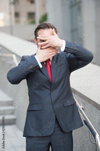 Waist up of entrepreneur hiding his face behind hands