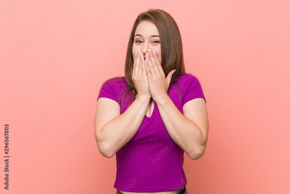 Young hispanic woman against a pink wall laughing about something, covering mouth with hands. Young hispanic woman against a pink wall laughing about something, covering mouth with hands.