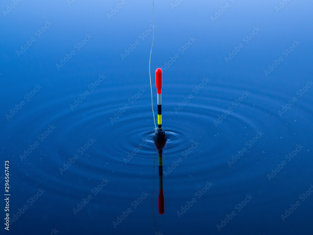 A fishing float floats on the water of the lake making circles in