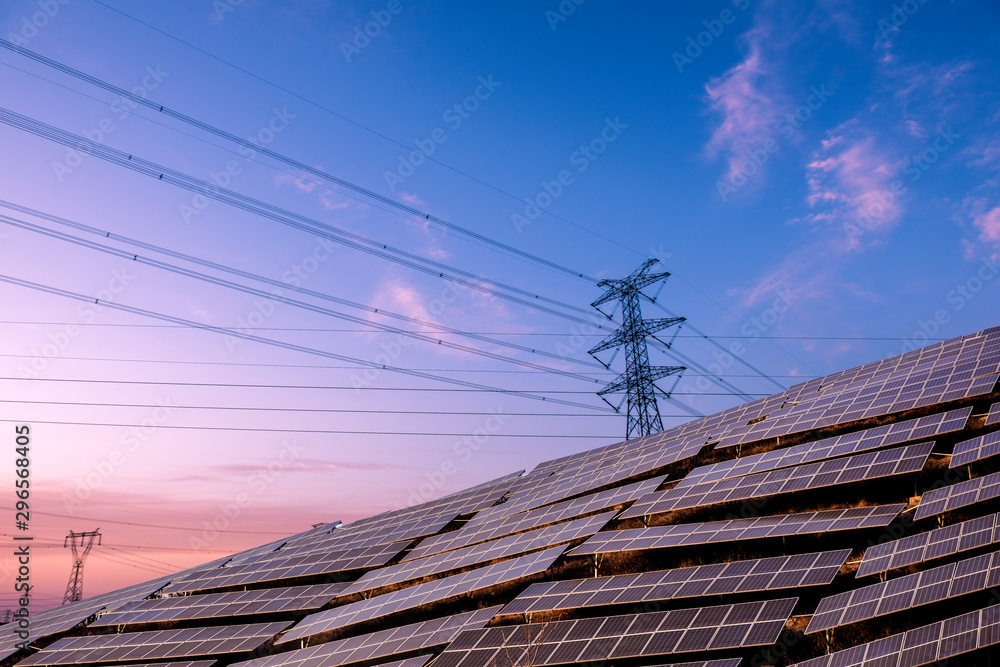 Solar photovoltaic panels and transmission towers at sunset. Alternative power sources - the concept of sustainable resources