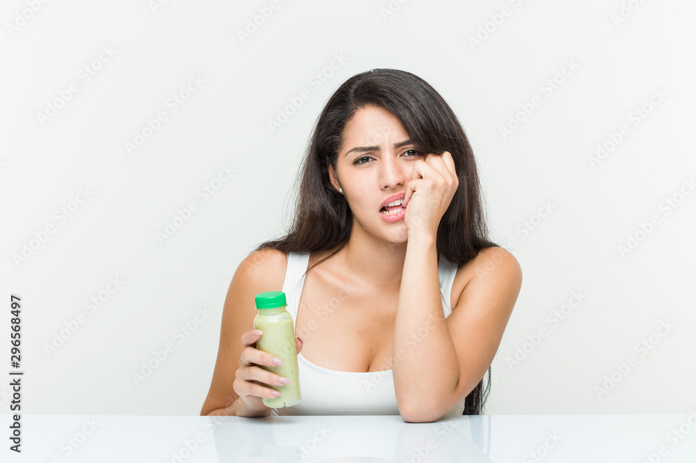 Young hispanic woman holding a vegetable drink biting fingernails, nervous and very anxious. Young hispanic woman holding a vegetable drink biting fingernails, nervous and very anxious.