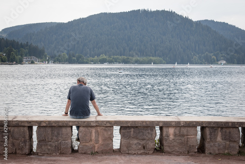 un homme assis au bord du lac de gérardmer regarde l'eau