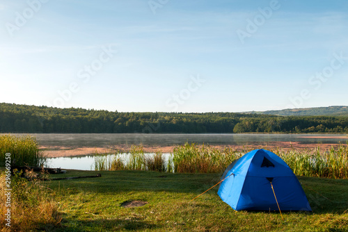 tent on the shore of a beautiful lake against a background of blue sky
