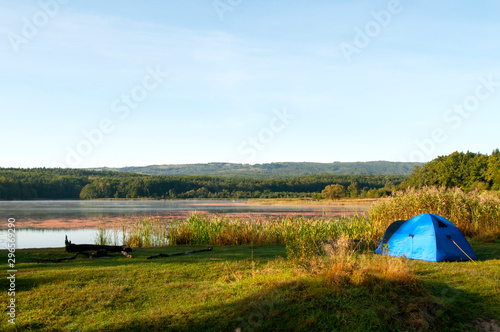 tent on the shore of a beautiful lake against a background of blue sky