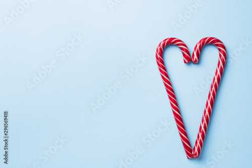 Christmas caramel canes heart shaped on a blue pastel background. Holiday festive celebration greeting card. with copy space to adding text.