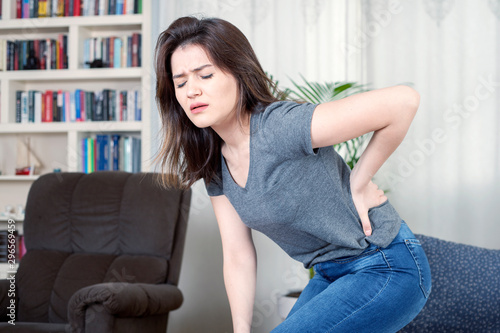 Free Download young woman sitting on sofa have backache  - GFXLoad