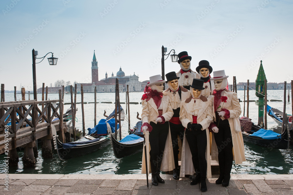 A group of people in masks for the Venice carnival in San Marco piazza, in the background the island of San Giorgio Maggiore. Italy
